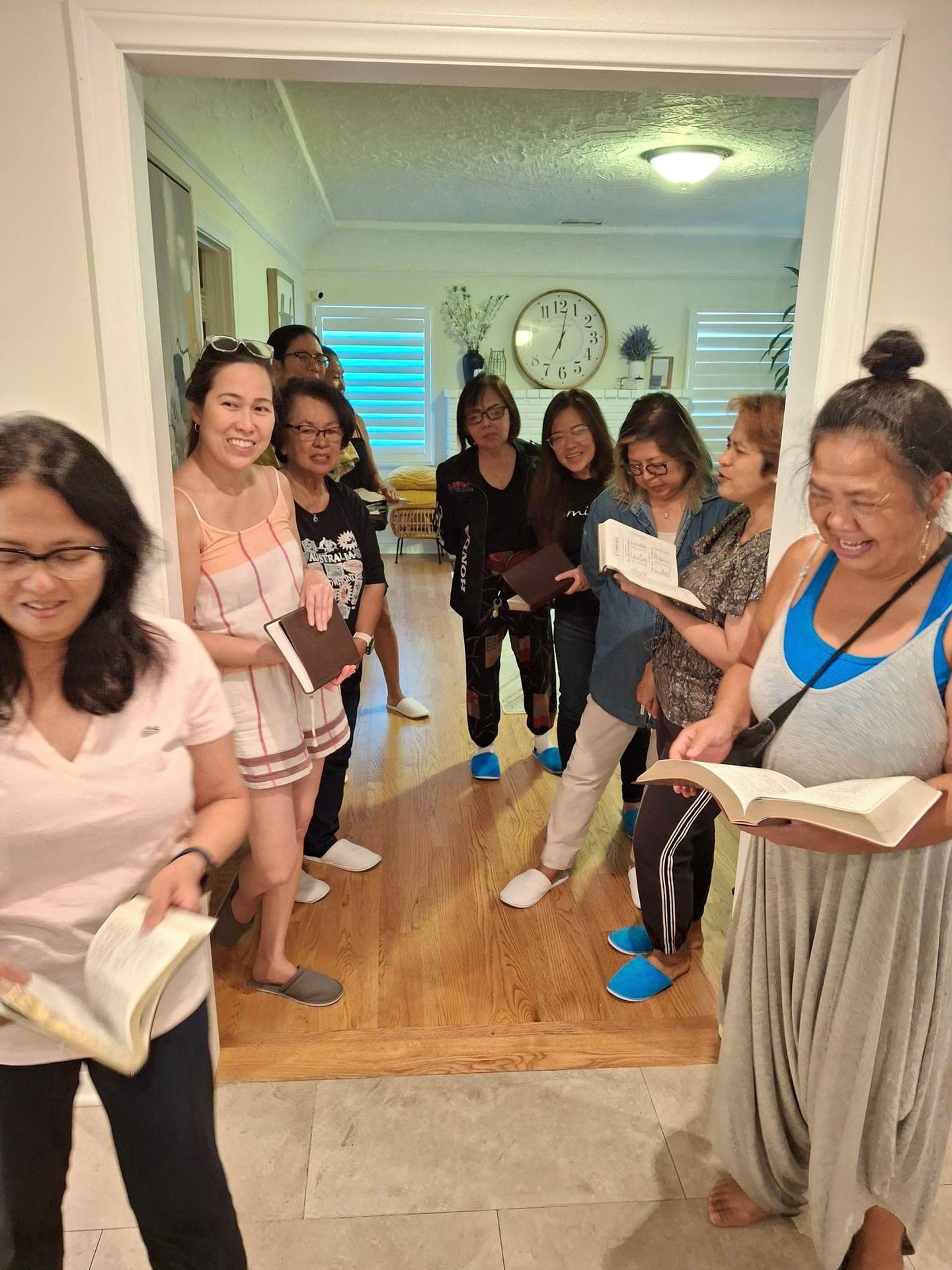 Group of people standing together indoors, smiling and reading from books.