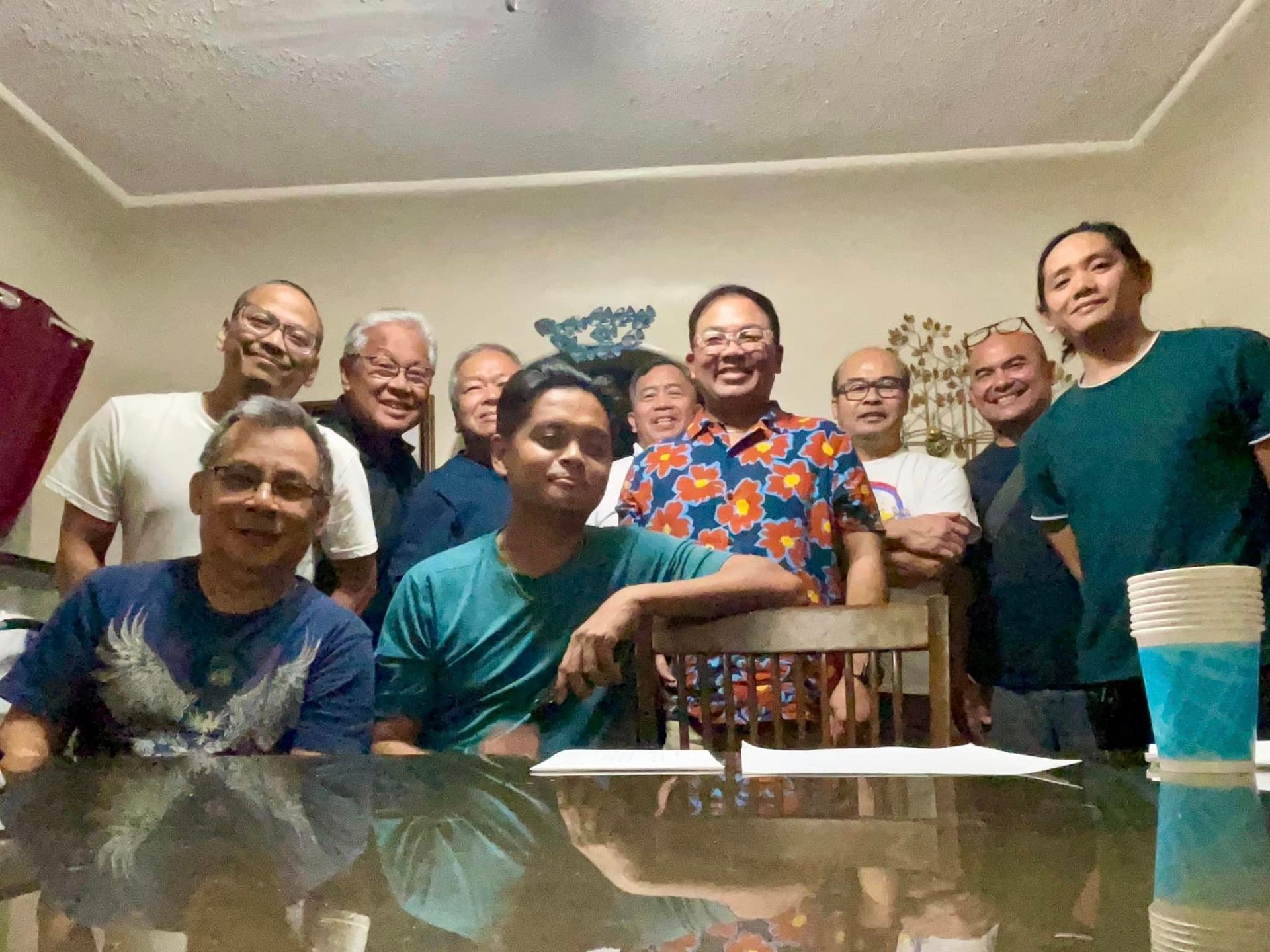 Group of smiling people standing around a table in a cozy room.